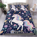 Unicorn duvet cover set on a bed with pastel rainbow manes, flowers, stars, and a navy background