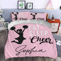 Pink cheerleading bedding displayed in a bedroom with matching pillowcases, black pom-pom silhouette, and bold lettering
