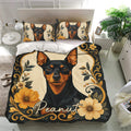 Black and tan Miniature Pinscher bedding set with golden floral accents displayed in a bright bedroom