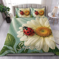 Ladybug duvet cover set displayed on a bed with daisies, green leaves, and a soft sage background