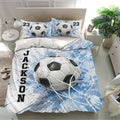 Blue soccer bedding set displayed in a bright bedroom with matching pillowcases and ball artwork