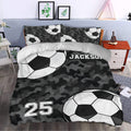 Soccer bedding set styled in a bedroom with black camouflage, large soccer balls, custom name, and number