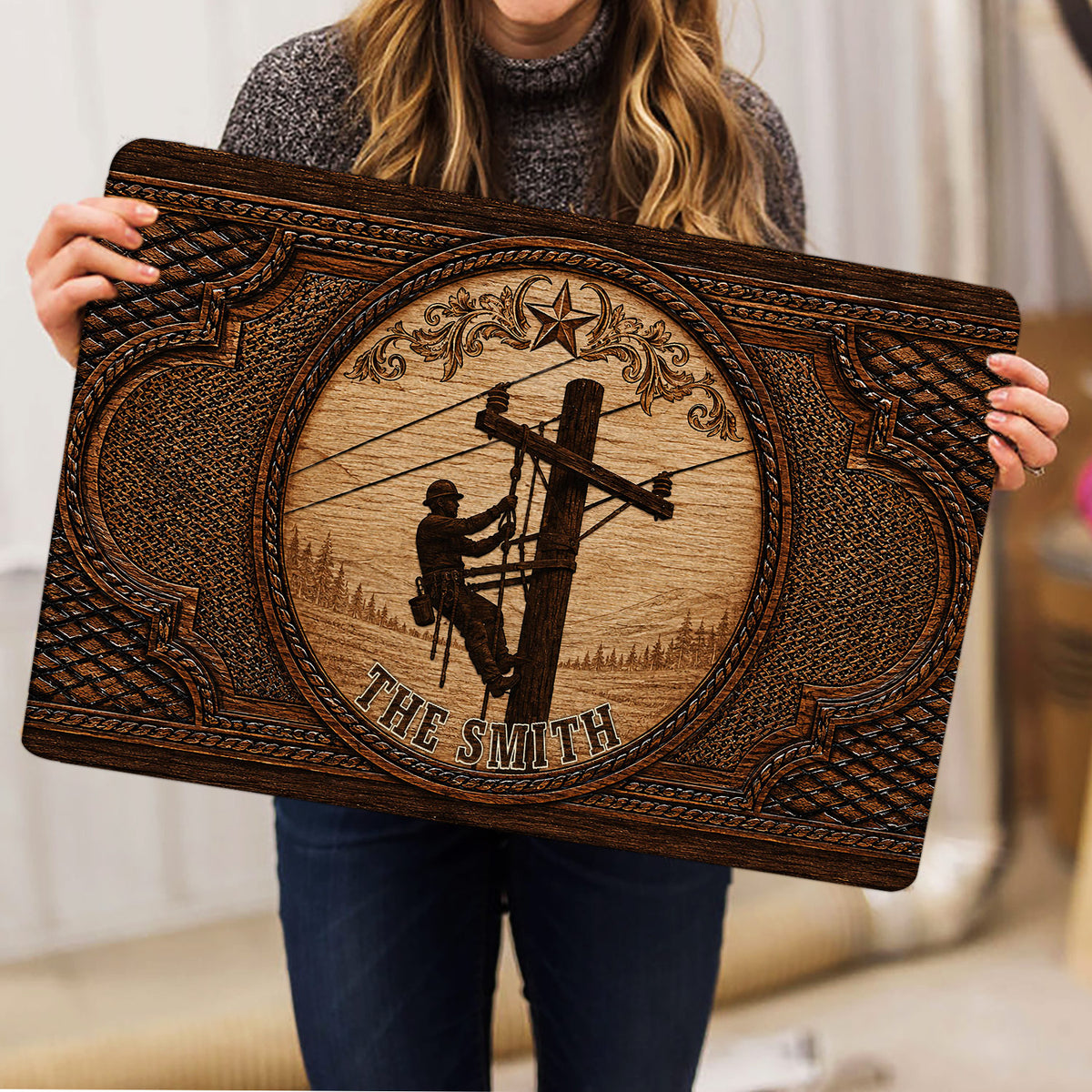 Lineman doormat held indoors, featuring a utility worker on a pole and detailed vintage-style border