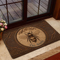 Bee-themed door mat positioned inside a glass doorway with floral accents and warm brown artwork