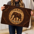 Elephant doormat held indoors, showing the ornate brown artwork and rounded corners