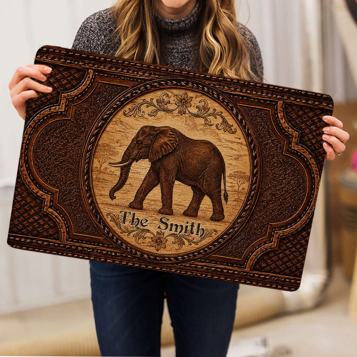 Elephant doormat held indoors, showing the ornate brown artwork and rounded corners