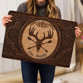 Person holding an ornate hunting doormat with deer skull, antlers, arrows, and rustic brown artwork