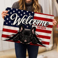 Person holding a French Bulldog doormat featuring a bold American flag welcome design
