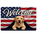 Custom family name welcome doormat featuring a golden yellow Labrador Retriever puppy peeking from beneath a folded American flag, red white and blue stars and stripes, bold Welcome lettering, and family name personalization.