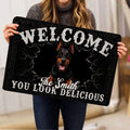 Person holding a black Doberman doormat featuring cracked stone artwork and bold welcome lettering