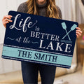 Lake house doormat shown in a home setting with navy artwork, aqua wood stripe and oar illustration