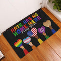 LGBT Pride doormat displayed in a home entryway on a wood floor with colorful heart artwork