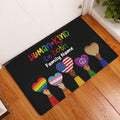 LGBT pride doormat displayed in a wood-floor entryway with colorful heart artwork