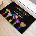 Black LGBT entryway mat featuring pride hearts and a welcoming message near a doorway