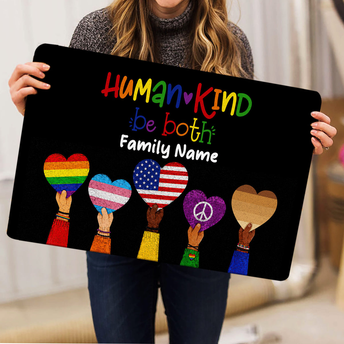 LGBT pride doormat held indoors, showing colorful hearts and a welcoming Human Kind design