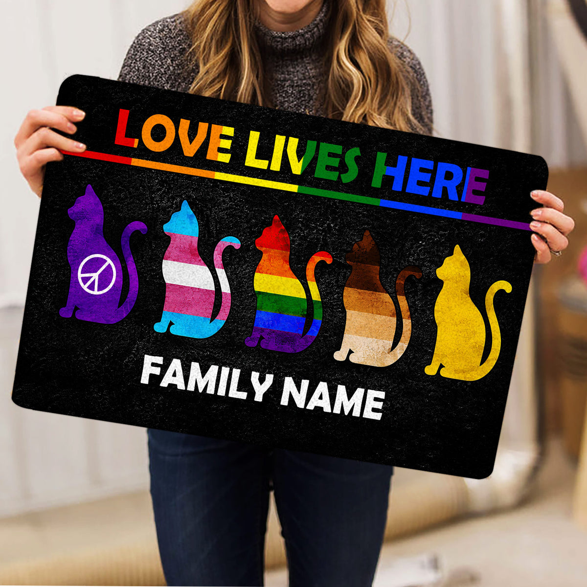 Person holding a colorful LGBT pride doormat featuring rainbow cat silhouettes