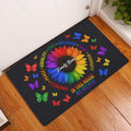 Rainbow sunflower LGBT doormat displayed in a bright entryway on a wood floor beside a white door