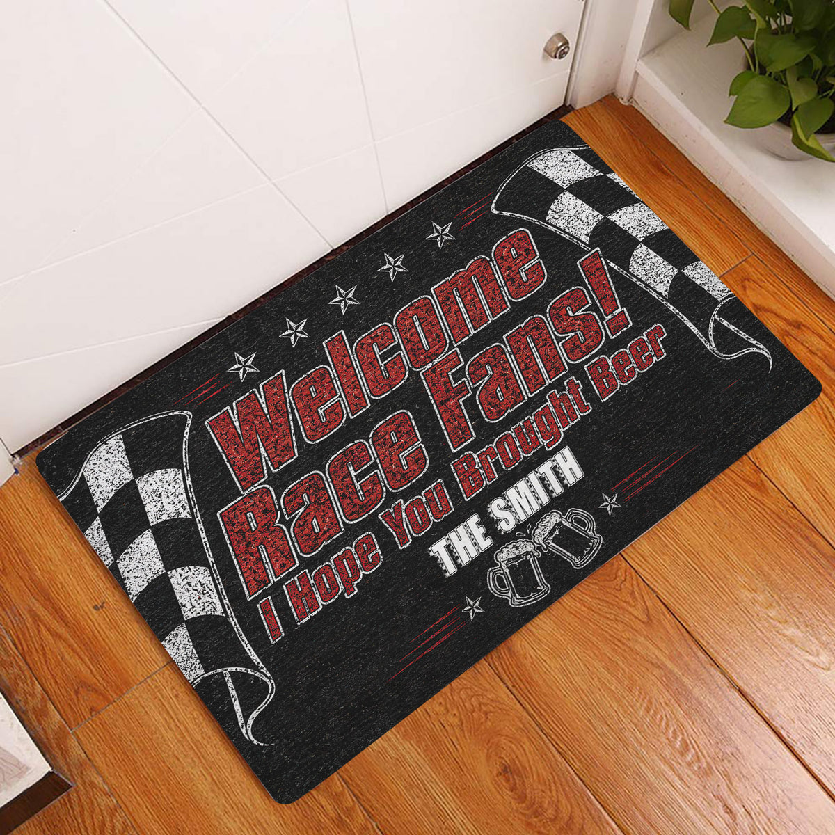 Racing-themed doormat displayed by an indoor door on a wood floor with checkered flag borders