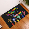 Colorful LGBT entryway doormat displayed on a wood floor near a white door