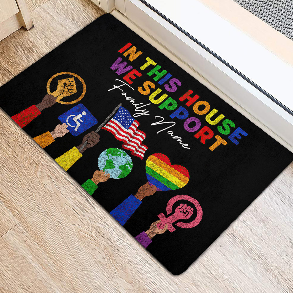 LGBT pride doormat arranged beside a doorway on light wood flooring