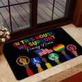 Colorful LGBT support doormat staged inside a glass doorway near flowers and a deck
