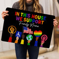LGBT pride doormat held indoors, showing colorful lettering, equality symbols, and raised fists