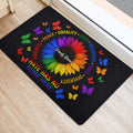 LGBT pride door mat positioned near an entrance with a colorful sunflower, butterflies, and inclusion messages