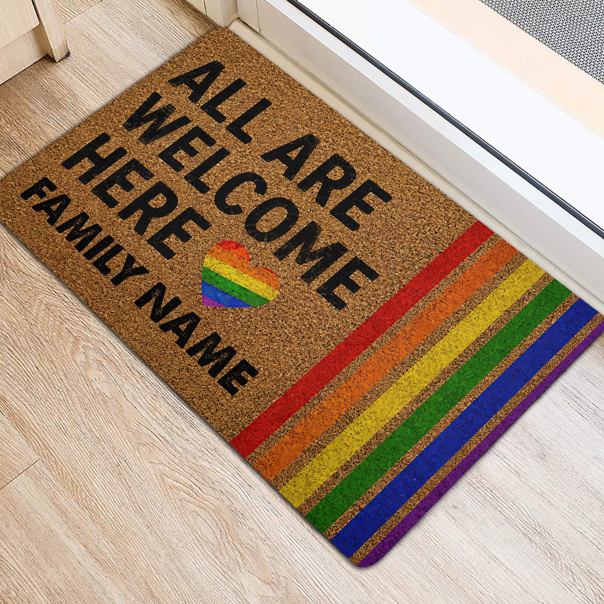 Rainbow LGBT welcome doormat placed by an interior doorway on a light wood floor