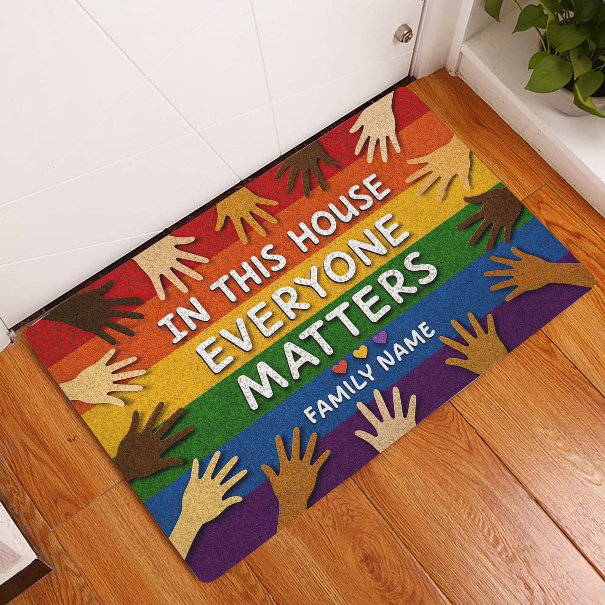 LGBT rainbow doormat displayed at a home entrance on a warm wood floor