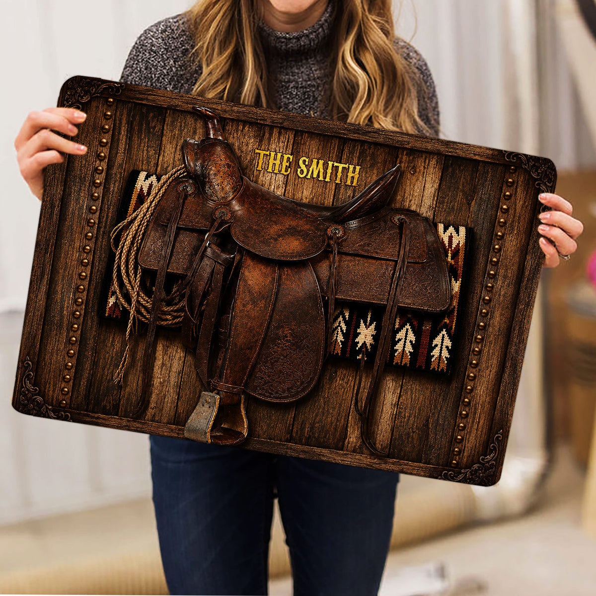 Person holding a rustic Western saddle doormat featuring rope and Southwestern textile artwork