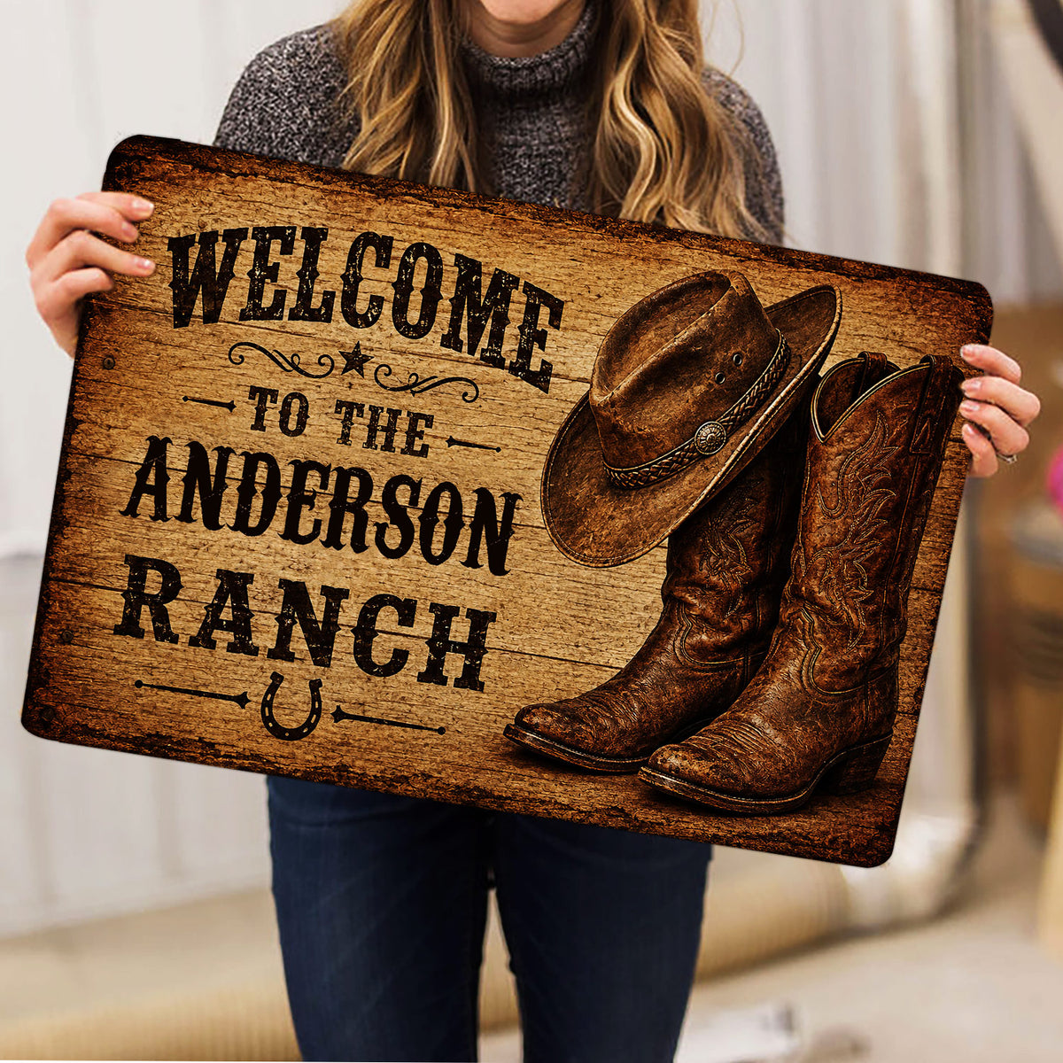 Person holding a rustic cowboy doormat featuring Western boots, hat, horseshoe, and ranch artwork