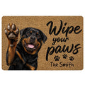 Rottweiler doormat design with a raised paw, tan textured background, paw prints, and welcoming script