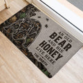 Bear door mat positioned at an entrance, showing the forest design, honey jar, leaves, and bold lettering