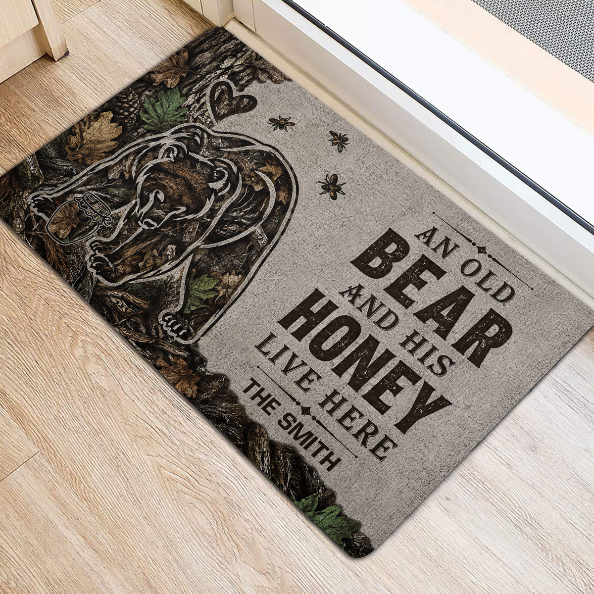Bear door mat positioned at an entrance, showing the forest design, honey jar, leaves, and bold lettering