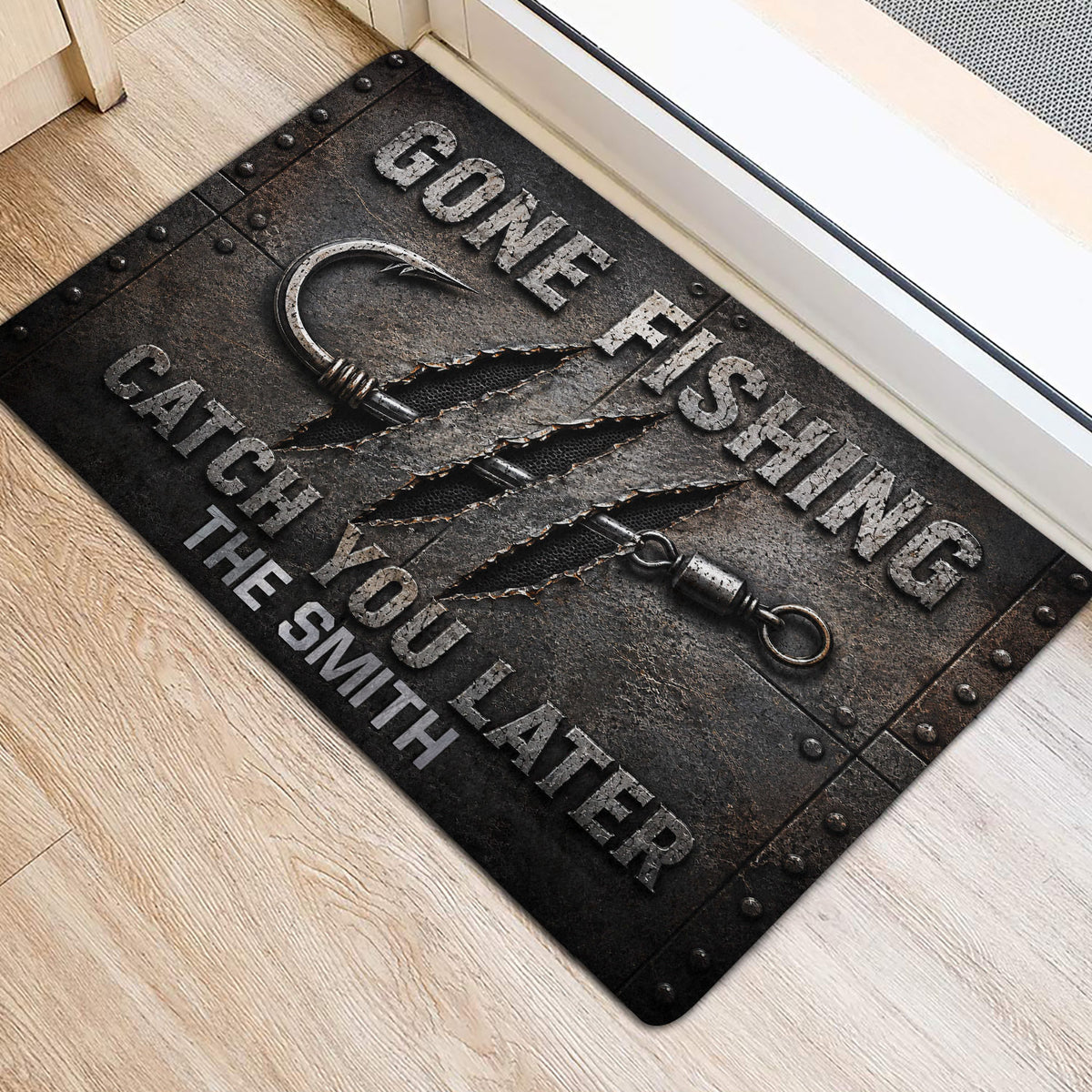 Dark fishing entryway mat featuring a hook, textured metal-style artwork, and bold fishing typography