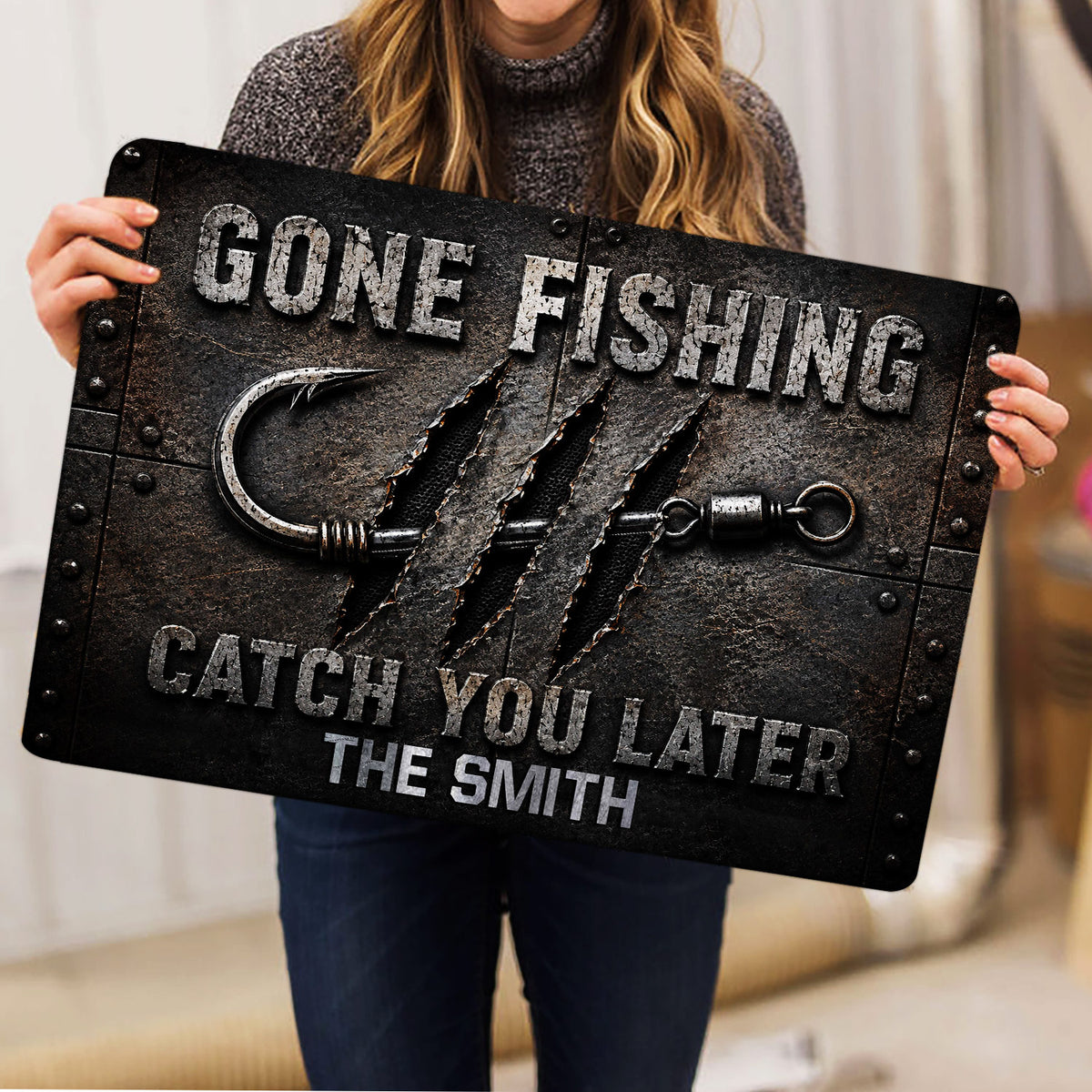 Angler-themed fishing doormat held indoors, showing a large hook and rugged dark artwork