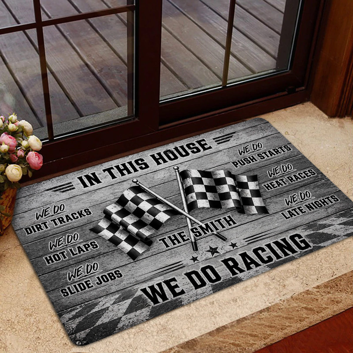 Racing-themed door mat styled in front of a glass door with checkered flags and vintage woodgrain graphics