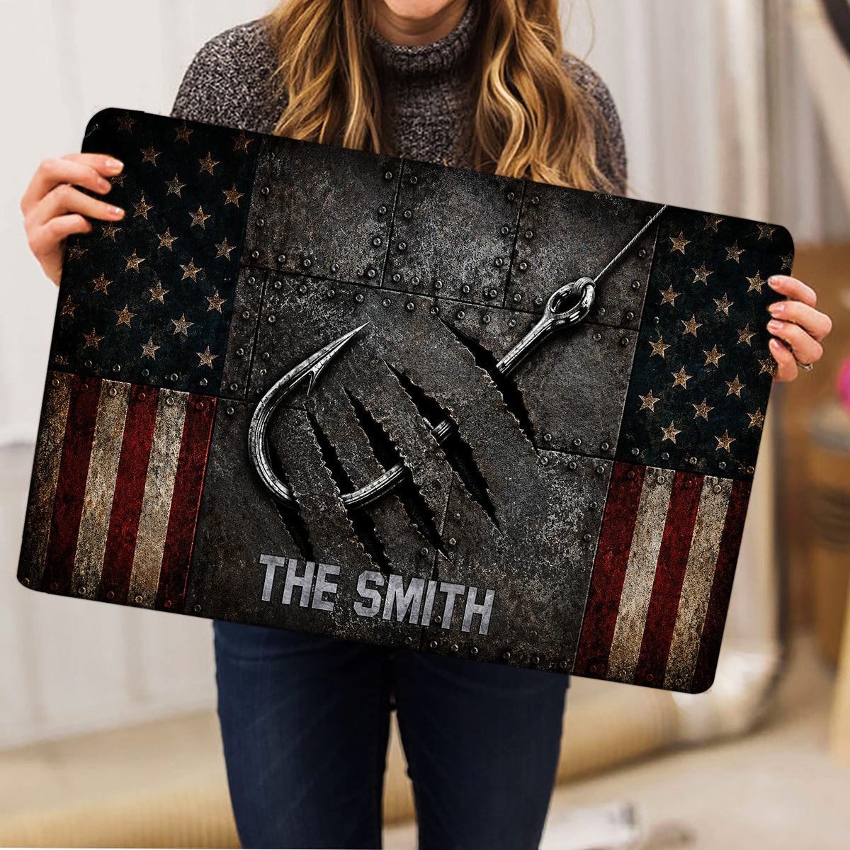 Person holding a rugged fishing-themed doormat featuring large hooks and a star-and-stripe border