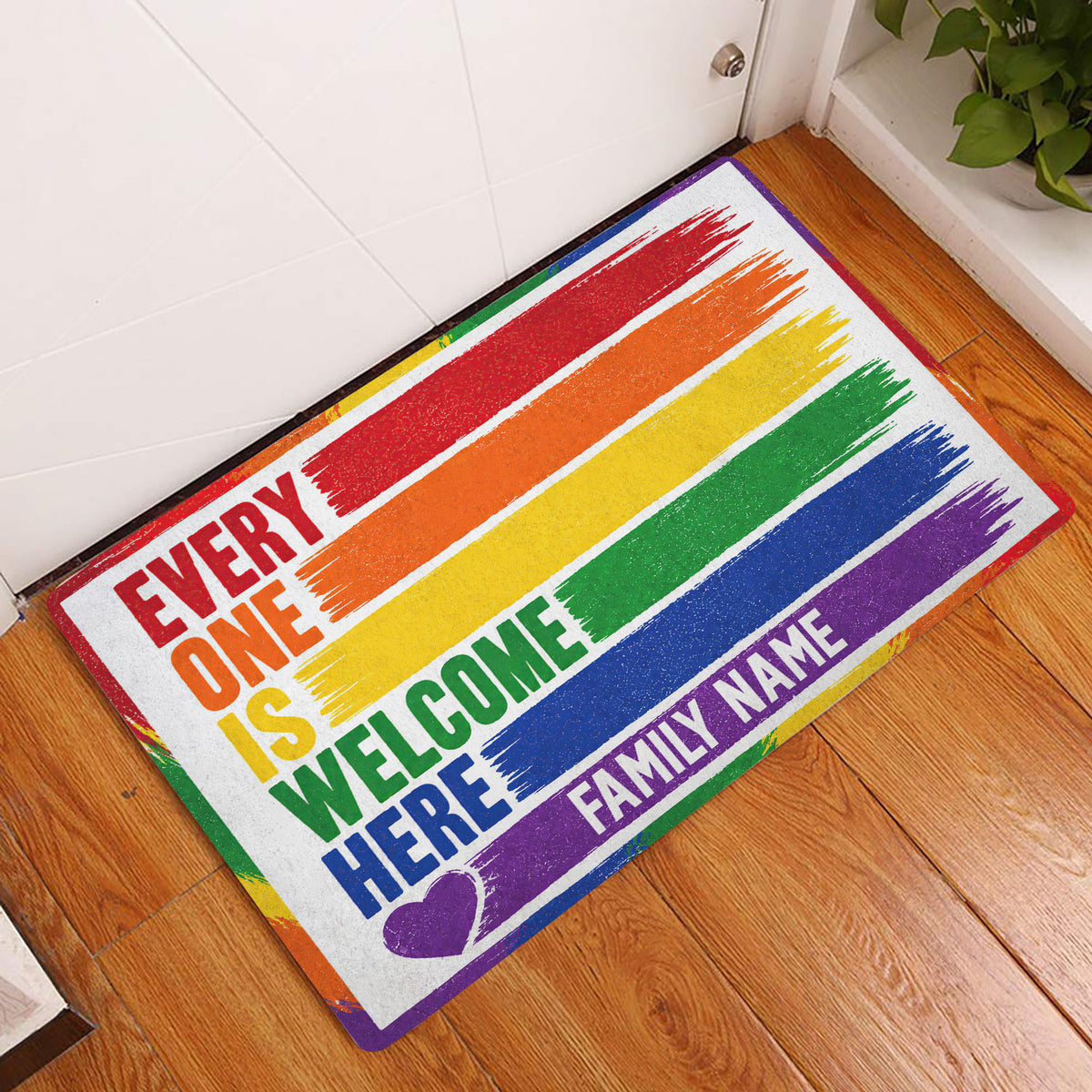 Rainbow LGBT pride doormat displayed in a bright home entryway beside a white door and wood flooring