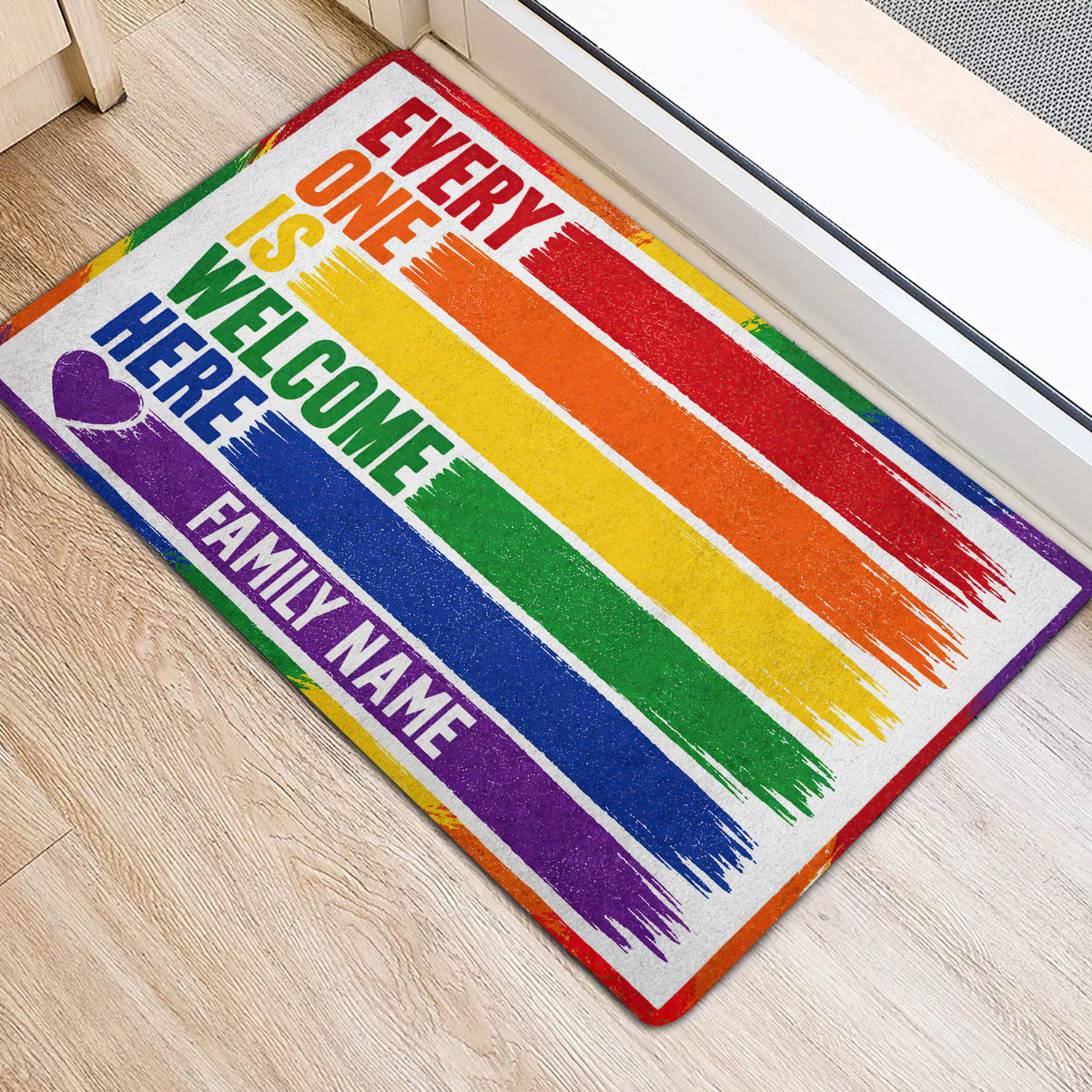 Colorful LGBT pride welcome mat positioned at an interior doorway on light wood flooring