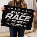 Racing doormat held indoors showing bold white lettering, star accents, checkered flags, and tire-track texture