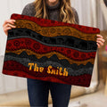 African-inspired elephant rug held indoors, showing detailed geometric bands and rich red and gold artwork