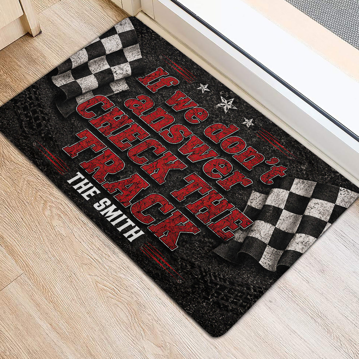 Black and red racing doormat with checkered flags positioned inside a doorway on light flooring