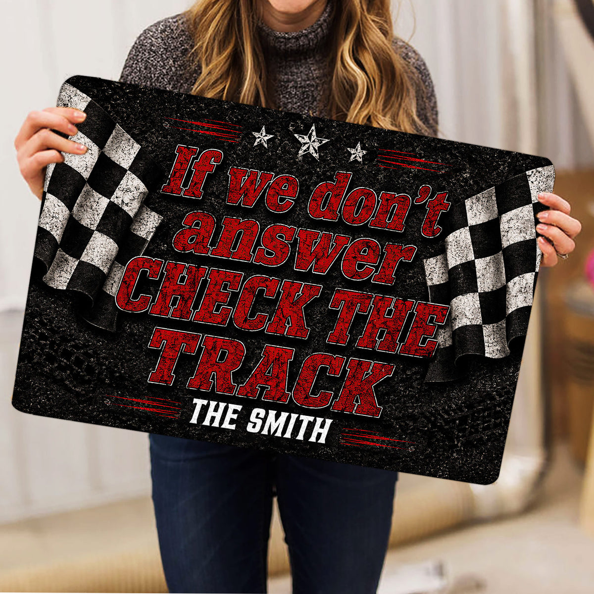 Racing doormat held indoors, showing the full black, red and white checkered flag design