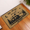 Camping entryway doormat displayed by a door with a camper, mountain, pine tree, and campfire design