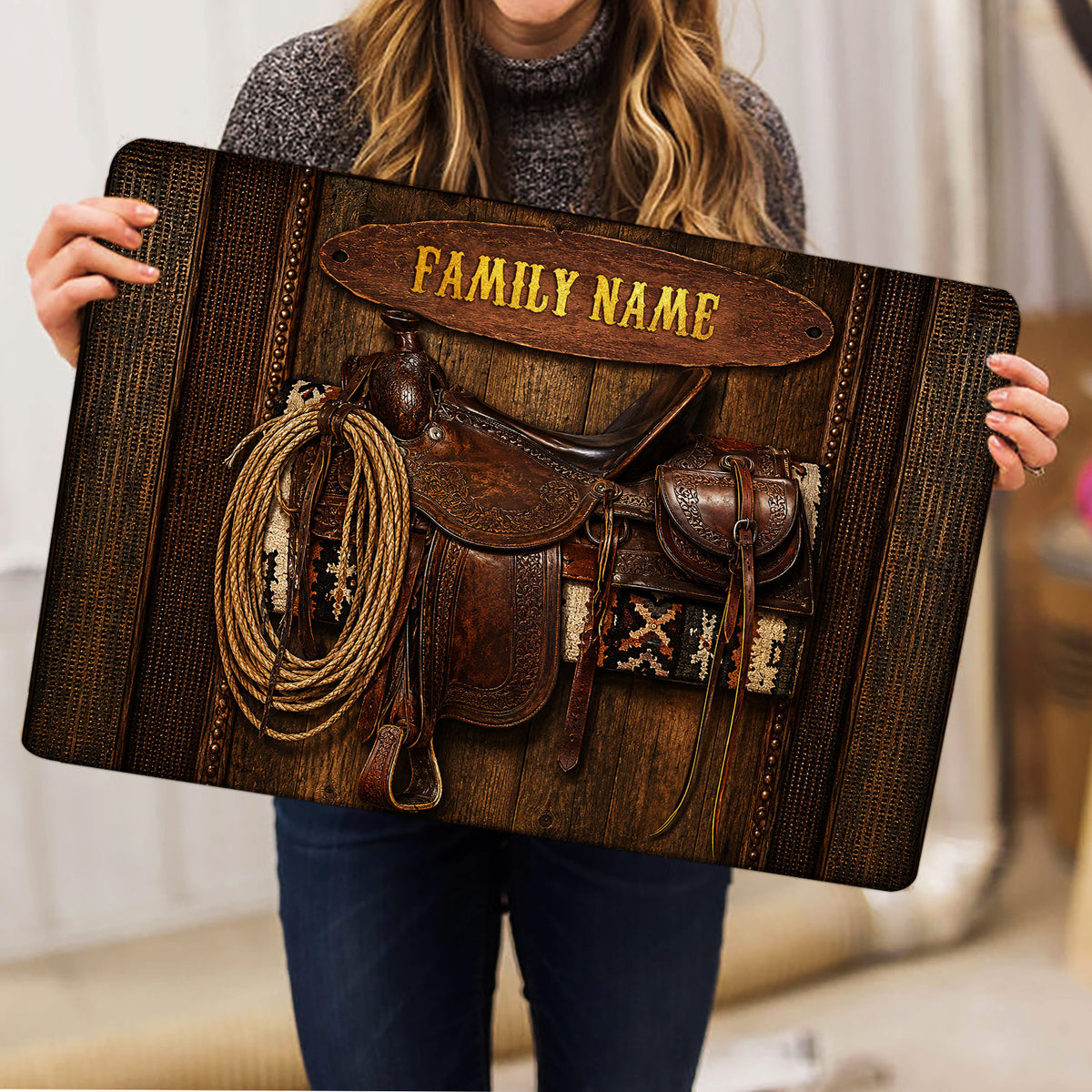 Person holding a cowboy-themed doormat with saddle, lasso and rustic western artwork