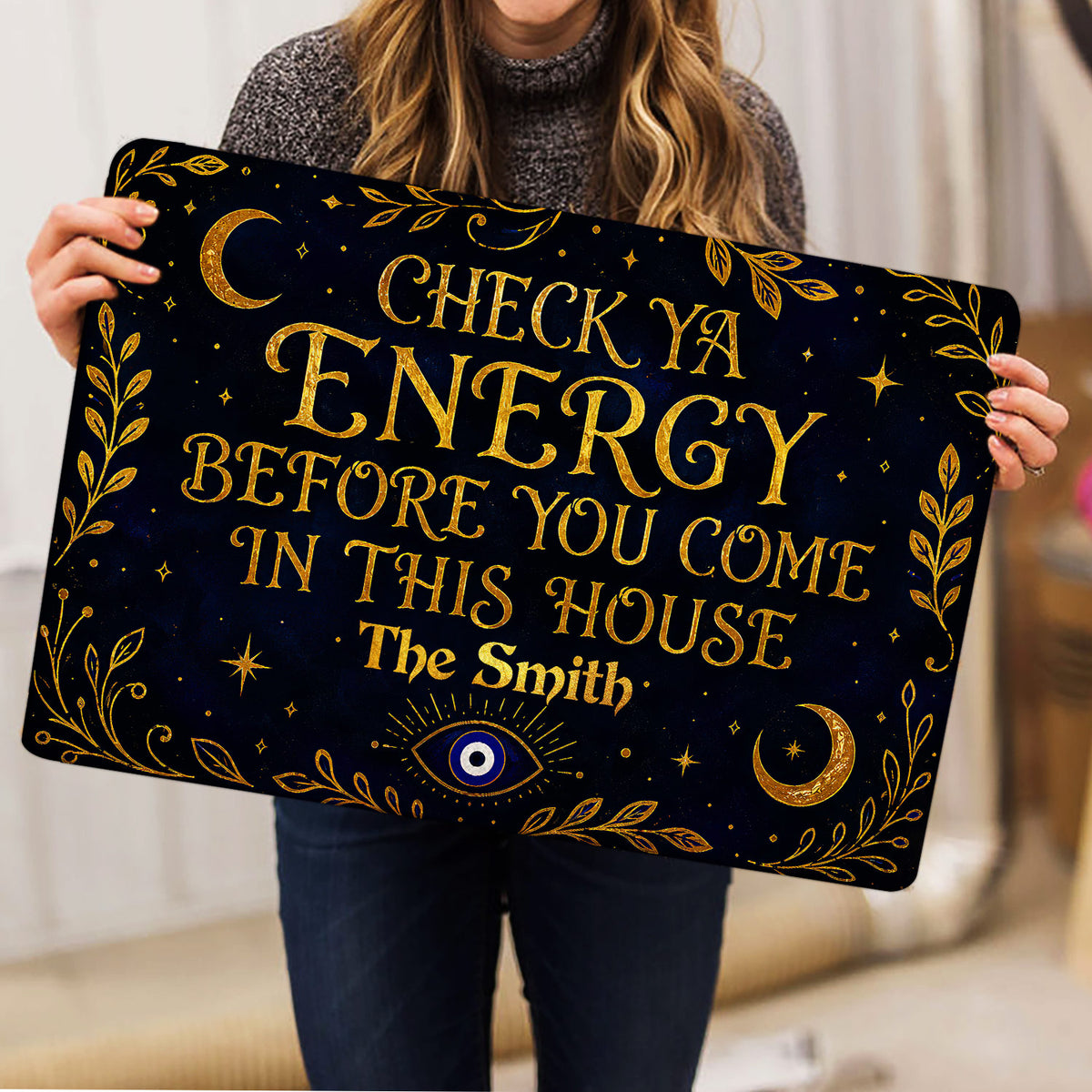 Evil eye doormat held indoors, displaying navy and gold celestial artwork with an eye symbol and moons