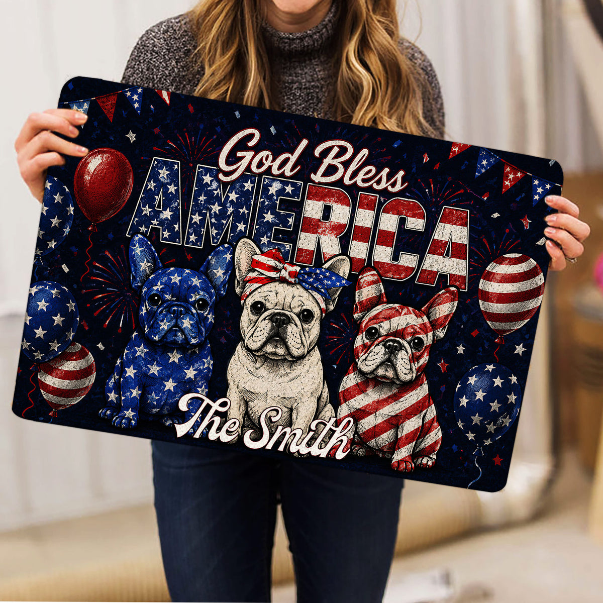 Person holding a patriotic French Bulldog doormat featuring three bulldogs and festive red white blue artwork
