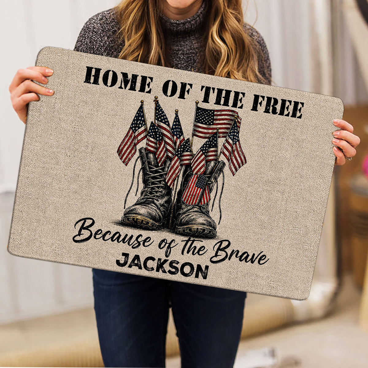 Person holding a patriotic veteran doormat featuring military boots and American flags