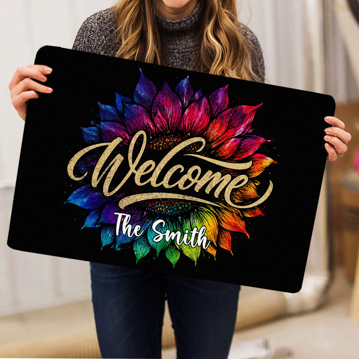 Woman holding a colorful sunflower welcome doormat indoors to show the full floral artwork